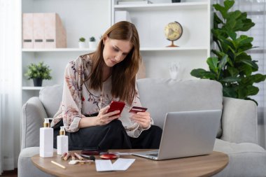 Genç mutlu kadın internetten alışveriş yaparak ürün satın alırken aynı zamanda internet üzerinden online ödeme sistemi ile çevrimiçi mağaza platformundan en yüksek siber güvenlik tarafından korunan ürünler sipariş ediyor.
