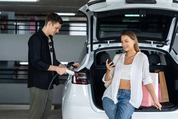 Młoda Para Podróżuje Samochodem Elektrycznym Centrum Handlowego Ładowanie Parkingów Centrum — Zdjęcie stockowe