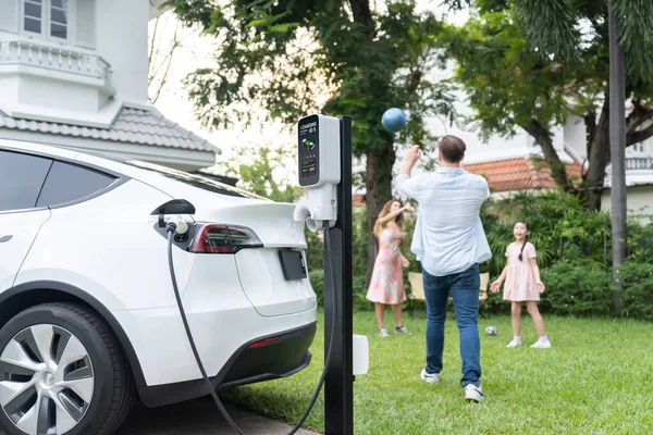 将家用电器充电站的电动车充电集中在模糊的背景下 快乐和欢乐的家庭一起玩耍 电动汽车使用替代的和可持续的能源来实现更好的未来 — 图库照片