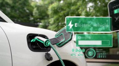 Elektrikli araba, doğal parktaki temiz enerji şarj istasyonundan gelen fütürist akıllı EV şarj cihazının dijital batarya durumu hologramıyla şarj oluyor. Gelecekçi çevre dostu EV araba. İnceleyin
