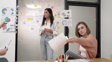 Profesyonel kadın lider, beyin fırtınası zihin haritası kullanarak yaratıcı pazarlama planını sunarken, iş arkadaşı da modern iş toplantı odasındaki uzman yatırımcılara toplantı belgelerini veriyor. Tertemiz..