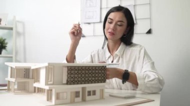 Profesyonel mühendis mimarın üçgen ölçekli ölçü evi modelini kullanarak modern ofisteki yapı uzunluğunu not alarak yakınlaşması. İş tasarımı. Tertemiz..