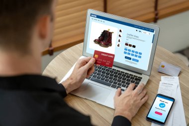 Genç adam internet bankacılığı için kredi kartlı dizüstü bilgisayar kullanıyor. İnternet üzerinden alışveriş yapıyor. Banka kartıyla modern ve kullanışlı online satın alma. Açılıyor