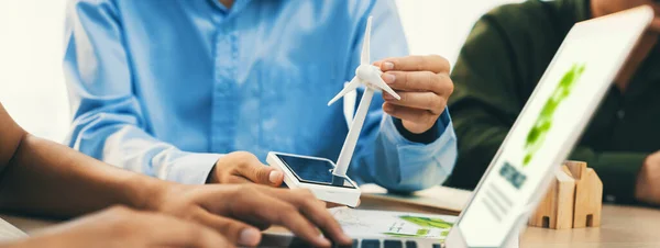 Professional businessman sees opportunity in the growing clean energy market at meeting room on table with windmill represented clean energy scatter around. Closeup. Focus on hand. Delineation