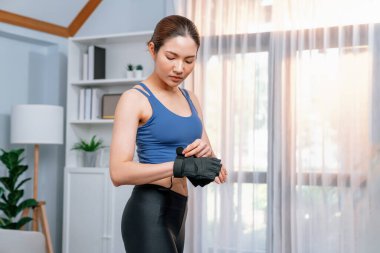 Genç Asyalı kadın portresi spor kıyafetleriyle evde egzersiz yapmadan önce kendini hazırlıyor. Oturma odasında ev içi fitness antrenmanı. Kuvvetli