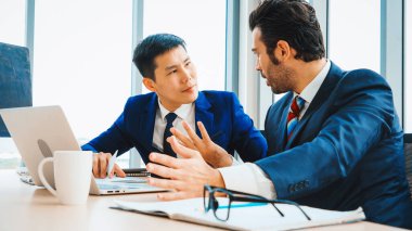 İki iş adamı toplantı odasında proje stratejisi hakkında konuşuyor. İş adamı, iş yerinde iş arkadaşlarıyla proje planlamasını tartışırken aynı zamanda mali raporla ilgili sohbet ve tavsiyelerde bulunuyor. Jivy