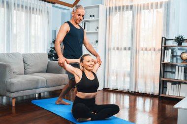 Spor giyim sektöründe aktif olan mutlu çift destekleyici ve evde yoga duruşunda birlikte yardımcı oluyorlar. Yoga egzersizi yapan sağlıklı bir erkek ve kadın yaşam tarzı. Etki