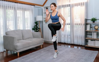 Enerjik ve güçlü atletik Asyalı kadın evinde koşuyor. Formda fiziğin takibi ve ev çalışması ve eğitimle sağlıklı yaşam tarzına bağlılık. Kuvvetli