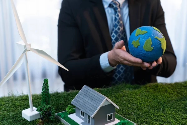 Eco business and save Earth concept shown by businessman or CEO holding paper globe in office with eco friendly mockup to promote CO2 and carbon footprint reduction for greener future. Quaint