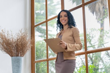 Klinikteki psikolog kadın. Profesyonel portresi. Dostane gülümsemesiyle hastayı psikoloğa davet ediyor. Deneyimli ve kendinden emin psikolog çok önemli bir uzmandır.