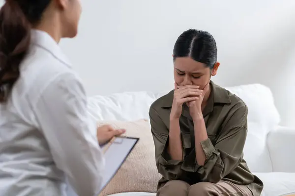 stock image Sad PTSD woman patient in uttermost therapy for mental health with psychologist, depression or grief after life failure. Frustrated trauma young woman talking to a psychologist about emotion in office