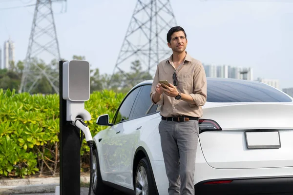 Uomo Paga Elettricità Con Smartphone Mentre Ricarica Batteria Dell Automobile — Foto Stock