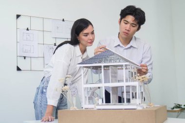 Kooperatif mühendis ekibinin portresi ev modelini ölçmek için cetvel ve mimari ekipmanlar kullanarak birlikte çalışıyor. Yaratıcı iş tasarımı ve takım çalışması konsepti. Tertemiz...