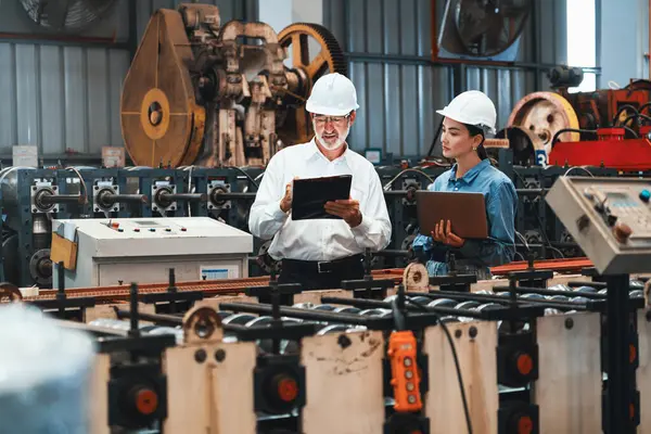 厂长与助手一起用笔记本电脑对钢铁工业机器进行检验 体现了在金属加工生产中作为机械工程检验主管的领导作用 — 图库照片