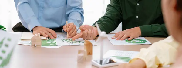 Green business meeting represented renewable energy. Skilled businesspeople discuss green business investment at table with environmental documents. Closeup. Focus on hand. Delineation.