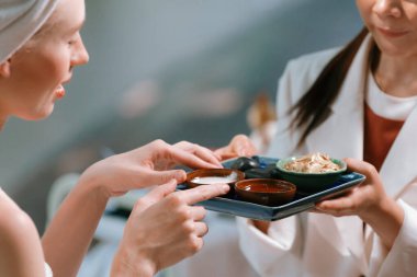 Güzel derili beyaz havluyla iki çekici beyaz kadının portresi tepside ev yapımı bitkisel yüz maskesi içeriyordu. Sağlıklı ve huzurlu bir kavram. Yakın çekim sükuneti.