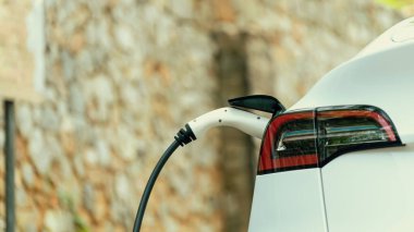 Panorama kapatma EV şarj kolu fişe takıldı veya elektrikli arabaya bağlandı, temiz çevre için sıfır CO2 emisyonu ile alternatif ve sürdürülebilir enerjiyle EV araba aküsünü şarj etti. Kalıcı