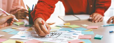 Bir grup genç iş adamı renkli yapışkan notlar hakkında fikir üretiyor. İş yerindeki toplantı odasında yapışkan bir nota yazarken başlangıç grubunun pazarlama stratejisinin portresi. Değiştirilmiş.