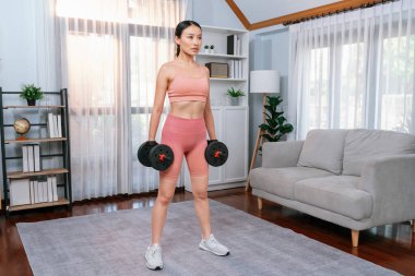 Güçlü enerjik kadın evde halter kaldırma egzersizi yapıyor. Genç atletik Asyalı kadın dayanıklılığı ve dayanıklılık antrenmanı. Ev ödevi olarak..