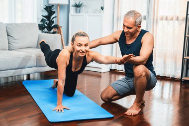 Spor giyim sektöründe aktif olan mutlu çift destekleyici ve evde yoga duruşunda birlikte yardımcı oluyorlar. Yoga egzersizi yapan sağlıklı bir erkek ve kadın yaşam tarzı. Etki