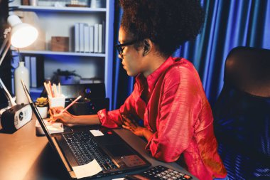 Çalışan Afrikalı kadın blogcu ciddi bir yüzle dizüstü bilgisayara yoğunlaştı, pazarlama veri analizlerini araştırdı, veri tabanındaki genel belge toplantı raporu için toplandı. Tatlandırıcı.