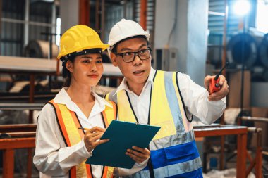 Fabrika ustabaşı ve mühendis endüstriyel çelik makinesi ve metal madde kalitesinde ürün teftişi yapıyor. Makine güvenliği ve kalite kontrollü üretim tesisi. Örnek gösteriliyor