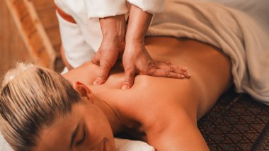 Beyaz güzel bir kadın ahşap sauna dolabının önünde sırt masajı yaptırıyor. Çekici bir kadın, aroma ve gerekli yağ ile çevrili derin bir rahatlama hisseder. Rahatlatıcı ve sakin bir kavram. Huzur.