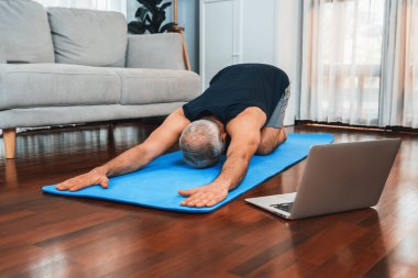 Spor giyim bölümündeki son sınıf öğrencisi evde egzersiz paspası üzerinde meditasyon pozisyonunda yoga yapıyor. Huzurlu ve huzurlu bir huzur içinde sağlıklı bir emekli yaşam tarzı. Etki
