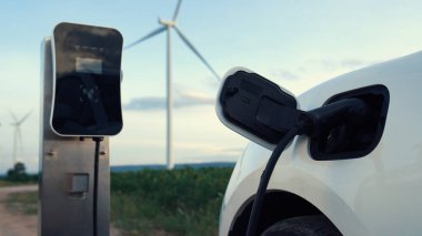 Çevreyi korumak için rüzgar türbininden yeşil ve yenilenebilir enerjiyle çalışan şarj istasyonunda şarj edilen gelişmiş gelecek enerji altyapısı konsepti.