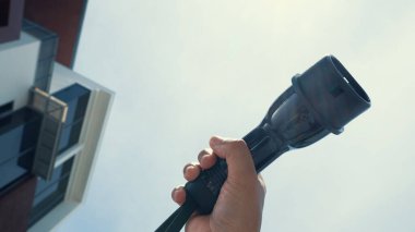 Yakın plan, çevresel kaygılar için alternatif sürdürülebilir temiz ve yeşil enerji kavramı olarak arka planda gün ortası gökyüzü ile elektrikli araç için bir EV kapsülü kavrıyor.