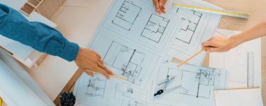 Mimari planlar toplantı masasında dağıtılırken profesyonel mimar el çabukluğu planlara işaret ediyor. Yaratıcı tasarım takım çalışması tartışma konsepti. Üst Manzara. Filizlenen.