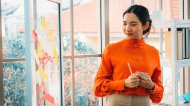 İş adamları ofisteki proje planlama kurulunda çalışıyor ve proje gelişimini analiz etmek için iş arkadaşlarıyla sohbet ediyorlar. Düzenli olması için cama yapıştırılmış yapışkan notlar kullanıyorlar. Jivy