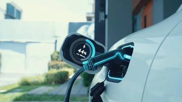 EV charger from home charging station plugged in and recharging electric car displaying digital battery status hologram. Smart and futuristic home energy infrastructure. Peruse