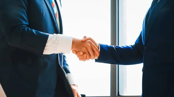 Business people handshake in corporate office showing professional agreement on a financial deal contract. Jivy
