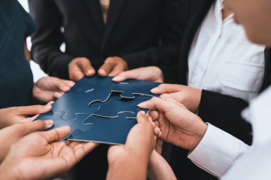 Çeşitli şirket çalışanları, ortaklık ve takım çalışmasını temsil etmek için bulmaca parçalarını birleştirerek ofiste işbirliği yapıyor. Yapboz 'u birleştirerek iş dünyasındaki birlik ve sinerji. Uyum