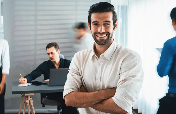 自信和快乐的微笑的商人肖像与模糊的运动背景 他的同事和在办公室工作的商业团队 办公室工作人员的团队精神和积极的工作观念 谨慎的人 — 图库照片