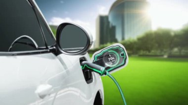 EV otomobili, elektrik yükleme istasyonuna bağlanarak yeşil parktaki EV şarj cihazının pil durumu hologramını şehrin gelecekteki ekolojik yaşam biçimi ve temiz enerjinin kullanımı olarak gösteriyor. İnceleyin
