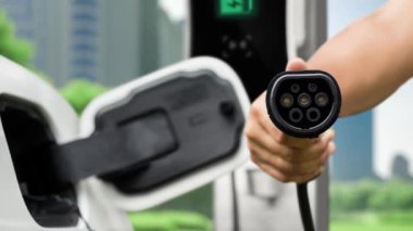 Kameranın önüne odaklanmış EV şarj cihazı fütüristik akıllı dijital EV batarya durum hologramını gösteriyor. EV araba şarjı sürdürülebilir güç için alternatif enerji kullanıyor. İnceleyin