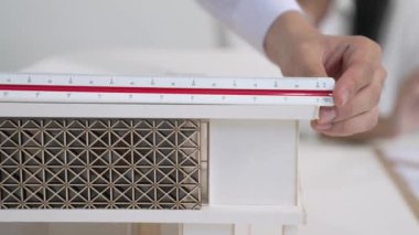Profesyonel erkek mühendis ev modelini cetvel kullanarak ölçerken güzel bir kooperatif iş arkadaşı verileri analiz etmek için dizüstü bilgisayar kullanarak birlikte çalışıyor. Yaratıcı tasarım ve takım çalışması. - Yakın çekim. Tertemiz..