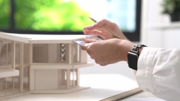 ルーラー測定ハウスモデルを使用して若い美しい白人建築家エンジニアの手を閉じ 現代のオフィスで青写真を書く クリエイティブでプロフェッショナルなデザインコンセプト インマキュライト — ストック動画