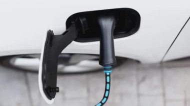 Elektrik yükleme istasyonundan parlayan ışık kablosu ile elektrik şarj etmek için elektrikli araca takılı üst görüntü EV şarj cihazı. Kesme-Sınır yeniliği ve gelecekteki yeşil enerji sürdürülebilirliği. İnceleyin