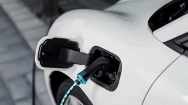 Şarj istasyonundan çevre dostu araba şarj oluyor. Fütürist hologram görüntü bataryası durumu. Alternatif enerji teknolojisinde son gelişmeler ve şarj edilebilir EV araba. İnceleyin