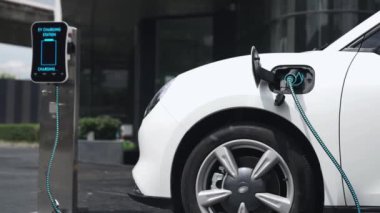 İş adamı, şehir merkezindeki şarj istasyonundan ya da otoparktan EV şarj aletini çıkardı. Şehir yaşam tarzında alternatif temiz enerji kullanan çevre dostu şarj edilebilir araba. İnceleyin.
