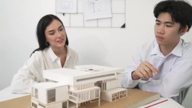 Profesyonel akıllı iş birliği mühendisi mühendis ekibi modern ofisteki ev yapısını planla kontrol ederken genç ve güzel proje yöneticisi not alıyor. Yaratıcı tasarım konsepti. Tertemiz...
