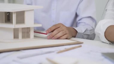 Profesyonel erkek mühendis ev modelini cetvel kullanarak ölçerken güzel bir kooperatif iş arkadaşı verileri analiz etmek için dizüstü bilgisayar kullanarak birlikte çalışıyor. Yaratıcı tasarım ve takım çalışması. - Yakın çekim. Tertemiz..