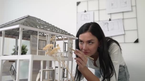 청사진이 벗겨진 사무실에서 연필을 사용하여 하우스 모델을 측정하는 아름다운 스마트 — 비디오