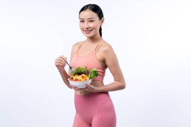 Spor giyim mağazasında elinde meyve ve sebze dolu salata kasesi tutan genç bir Asyalı kadın. Doğal gençlik ve uygun vücut yaşam tarzı izole edilmiş arka planda dengeli beslenme. Kuvvetli