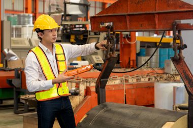 Makine operatörü çelik üretim makinelerini ustalıkla çalıştırıyor, metal fabrikasındaki ağır inşaat mühendisliği malzemeleri için silindir rulo çelik üretiyor. Örnek gösteriliyor