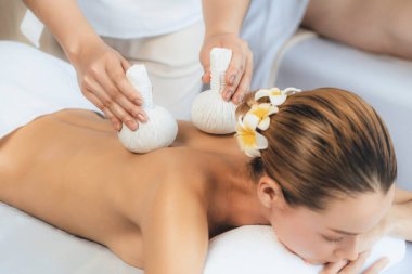 Sıcak bitkisel top spa masaj vücut tedavisi, masör nazikçe bitki torbasını çift müşteri vücuduna bastırıyor. Aromaterapi dinlenme sükuneti ve sükuneti kaplıca salonundaki atmosferi aydınlatıyor. Sessiz.