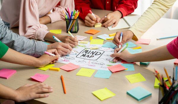 Creative business team brainstorming about marketing strategy and business plan by using mind mapping. Startup team work together to write down on paper. Focus on hand. Closeup. Variegated.